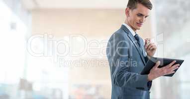 Businessman holding tablet in large bright modern hall