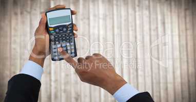 Hands with calculator against blurry wood panel