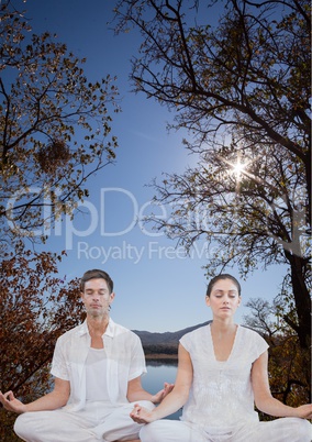 Woman and man doing yoga in front of a lake and mountains