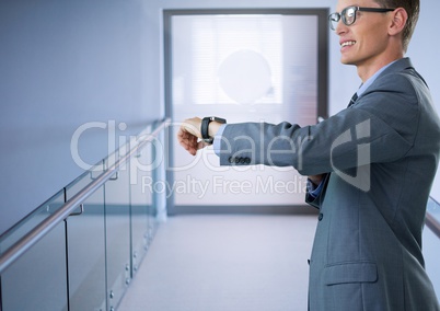 Businessman holding smart watch in corridor