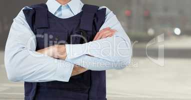 Security guard mid section arms folded against blurry street