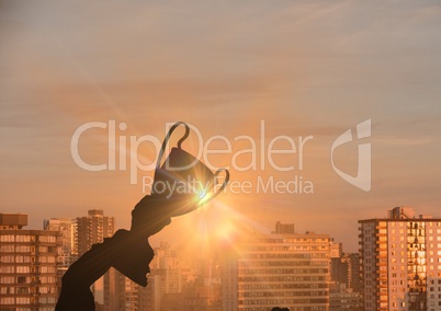 business hand with trophy (shade). city sunset