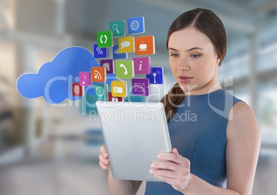 Businesswoman holding tablet with cloud apps icons in bright space hall