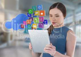 Businesswoman holding tablet with cloud apps icons in bright space hall