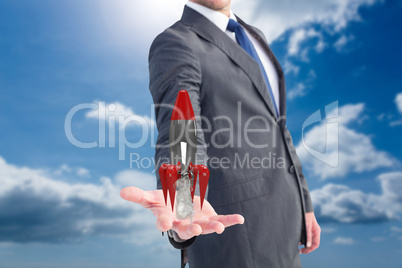 Businessman holding a rocket in his hands with blue sky background