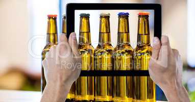 Hands photographing beer bottles through digital tablet at bar