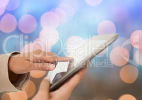 Hand touching tablet with sparkling light bokeh background