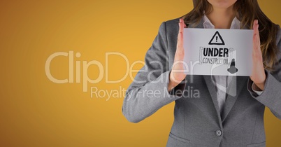 Business woman mid section with card showing grey construction doodle against yellow background