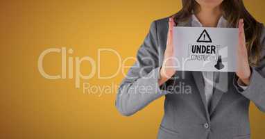 Business woman mid section with card showing grey construction doodle against yellow background