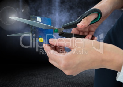 Hands cutting bank card with dark background