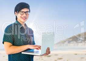 Trendy man with laptop against blurry beach