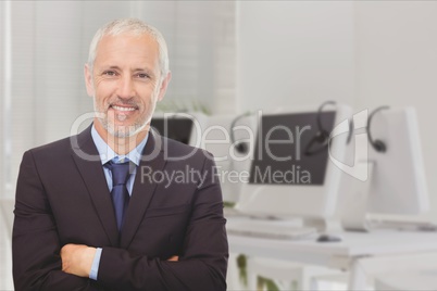 Businessman with crossed arms standing on against office background