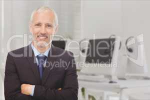 Businessman with crossed arms standing on against office background