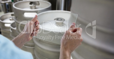 Cropped hands photographing kegs through transparent device at brewery