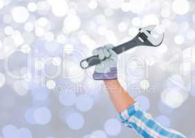 Hand with wrench and sparkling light bokeh background