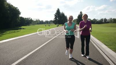 Cheerful adult fit women jogging in the park