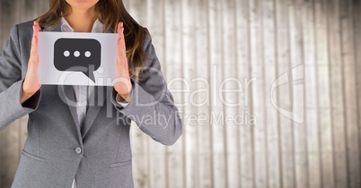 Business woman mid section with card showing speech bubble graphic against blurry wood panel