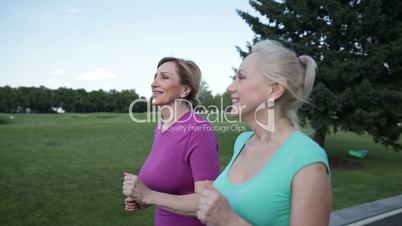 Two pretty senior females joggers training in park
