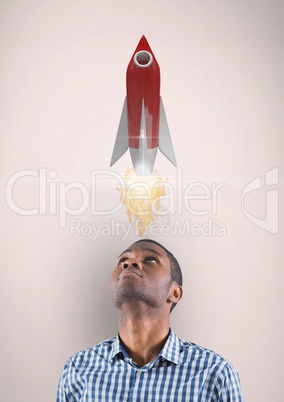 Digital image of man looking up at rocket launch while standing against beige background