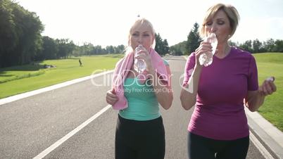 Fitness senior women drinking water after jogging