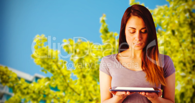 Composite image of young brunette holding digital tablet