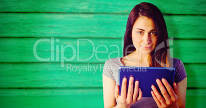 Composite image of portrait of brunette holding digital tablet