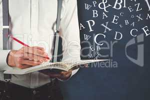 Composite image of mid section of man writing on book