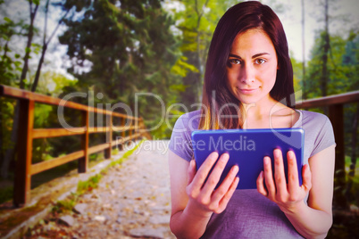 Composite image of portrait of brunette holding digital tablet