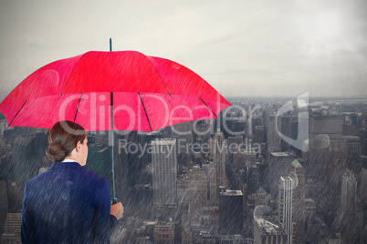 Composite image of rear view of businesswoman carrying red umbrella