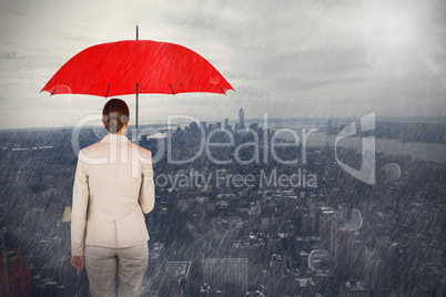 Composite image of rear view of female executive carrying red umbrella