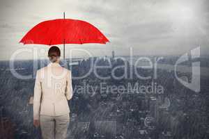 Composite image of rear view of female executive carrying red umbrella