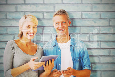 Composite image of portrait of couple with digital tablet and mobile phone