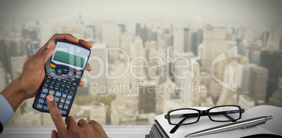 Composite image of hands of businessman using calculator