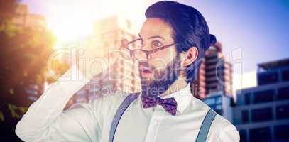Composite image of surprised man holding eyeglasses while looking away