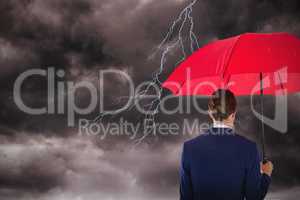 Composite image of rear view of businesswoman holding red umbrella