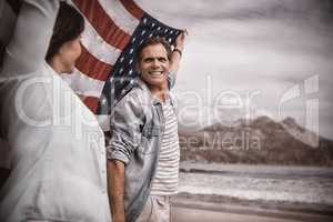 Mature couple holding American flag on beach