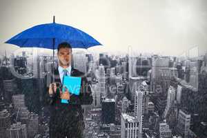 Composite image of portrait of serious businessman holding blue umbrella and file