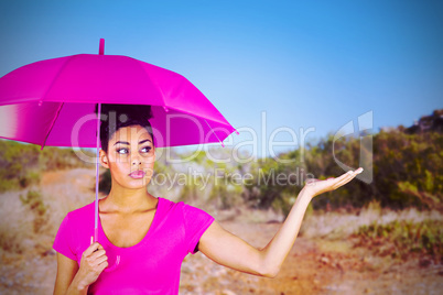 Composite image of young woman carrying pink umbrella