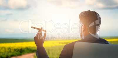 Composite image of rear view of businessman holding cigar