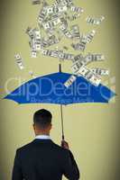 Composite image of rear view of businessman carrying blue umbrella