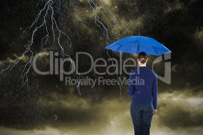 Composite image of rear view of businesswoman holding blue umbrella