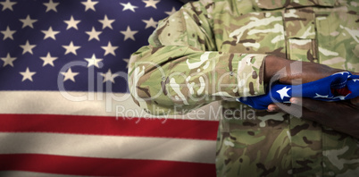 Composite image of mid section of soldier holding american flag