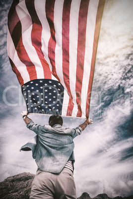 Rear view of man holding american flag against sky