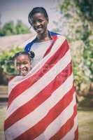 Portrait of mother and daughter wrapped in American flag at park