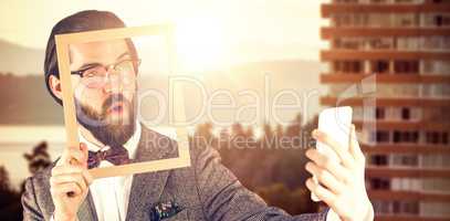 Composite image of businessman taking selfie while holding frame