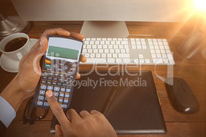 Composite image of hands of businessman using calculator