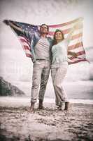 Full length of couple holding American flag against sky