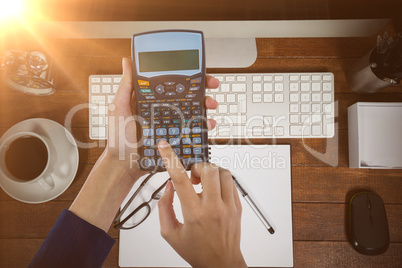 Composite image of hands of businesswoman using calculator