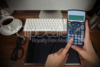 Composite image of hands of businesswoman using calculator