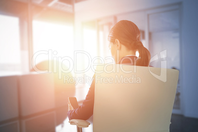 Composite image of rear view of businesswoman using mobile while sitting on chair